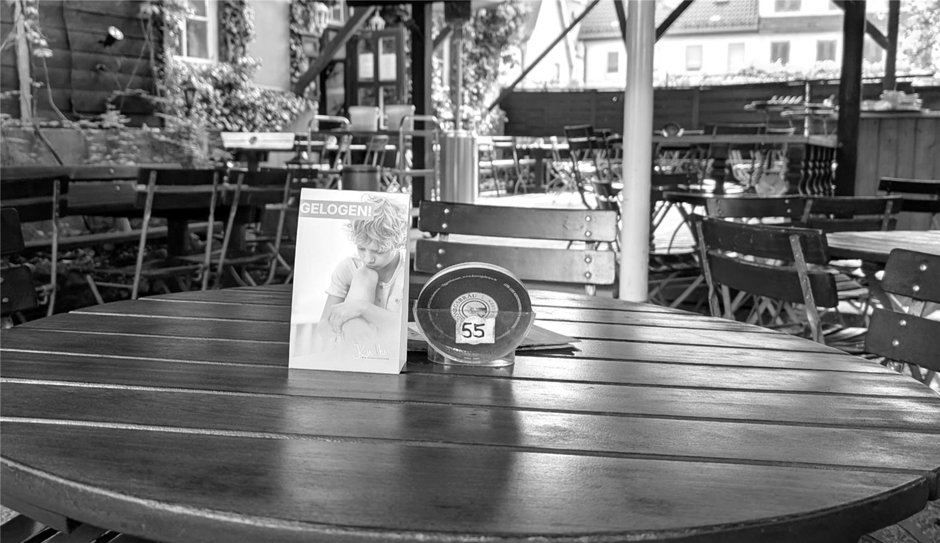 Aktionsaufsteller auf einem Tisch in einem Gastronomiebetrieb in Heidenheim. Der Aufsteller erzählt die Geschichte eines Kindes und ist Teil einer Kampagne, die auf fehlende Teilhabechancen von Kindern aufmerksam macht. Im Hintergrund sind Tische und Stühle im Außenbereich des Restaurants zu sehen.